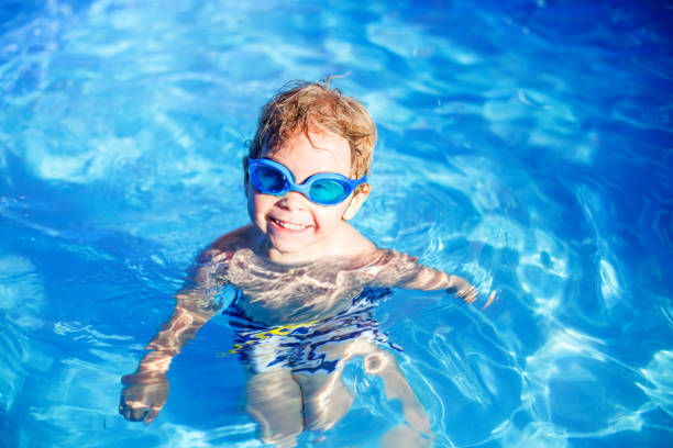 Beautiful toddler child, blond boy, swimming in a pool in backyard Beautiful toddler child, blond boy, swimming in a pool in backyard on sunset shallow stock pictures, royalty-free photos & images