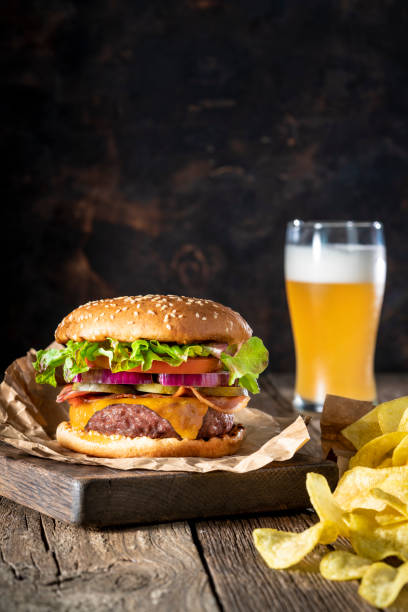 cheeseburger burger patty classico con patatine fritte e menu di birra su tavolo rustico di legno - roasted sesame seeds foto e immagini stock