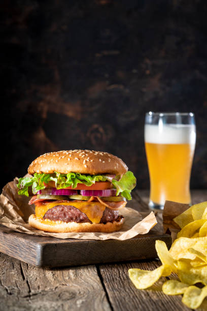 istock Cheeseburger Burger Patty classic with potato chips and beer menu on rustic table of wood 1325880567