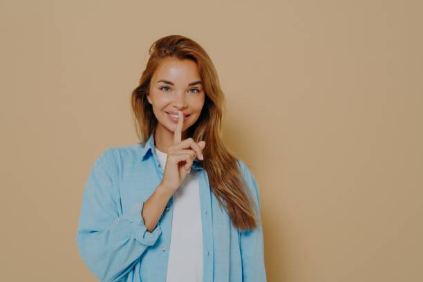 istock Excited woman showing silence gesture on beige background 1325882274