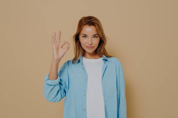 istock Young lady expressing approval with okay gesture on beige background 1325882324