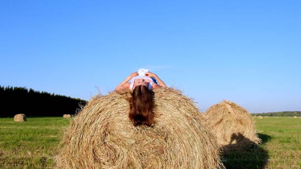 istock young female lies on a haystack and throws his hat. Rural area. freedom concept 1325882331