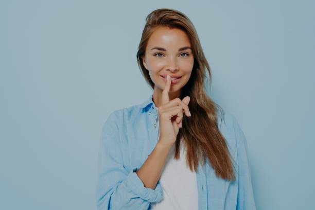 Pretty female placing fingers on lips making sign symbol