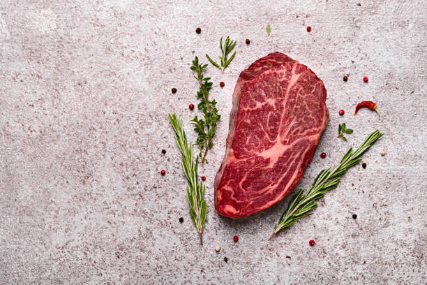 istock Fresh marbled beef rib eye steak and spices on grey stone background, copy space 1325883287