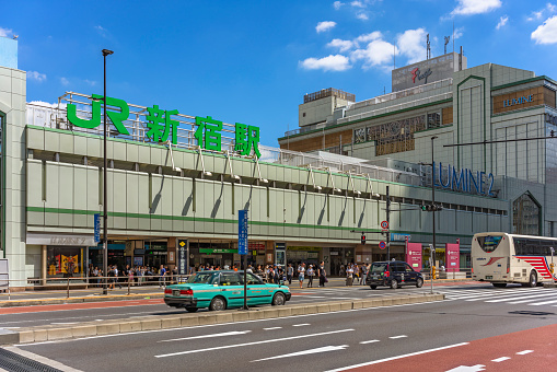 tokyo, japan - august 05 2019: Facade of the South Gate of the Japan Railway Shinjuku train station and the Lumine 2 shopping mall along the Ksh Kaid route with taxis and buses running.