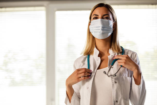istock Young female doctor in protective face mask putting on a stethoscope 1325887857