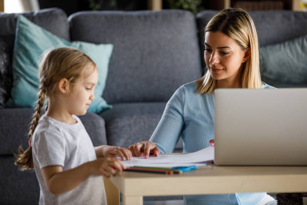 istock Little girl drawing while her mother is using laptop 1325888077