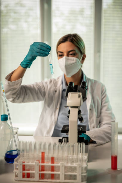 istock Female laboratory technician looking at liquid sample in a test tube 1325889582