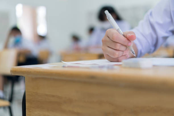 Asian Students testing in exam exercise taking at high school or university in test room. Hands hold pencil reading document paper on wooden desks classroom, Back to school for evaluation measurement estudiantes asiáticos que prueban en el ejercicio del examen que toma en la high school secundaria o la universidad en la sala de prueba. las manos sostienen el lápiz leyendo papel de documento en el aula de escritorios de madera, regreso a la escuela pa