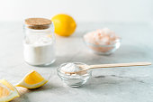Eco friendly natural cleaners, jar with baking soda, lemon, pink salt and wooden spoon on marble table background. Organic ingredients for homemade cleaning. Zero waste concept