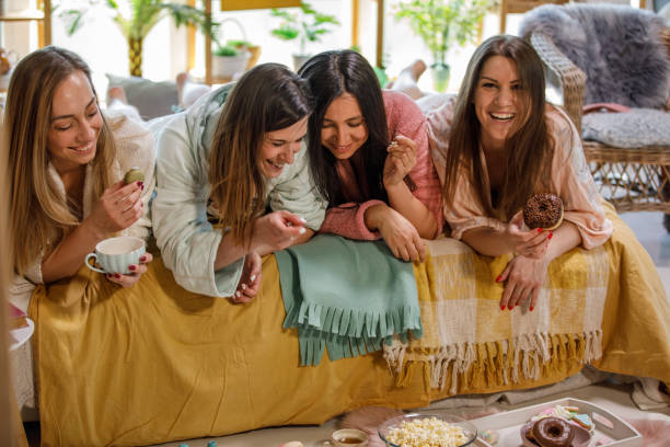 istock Four cheerful women enjoying snacks while relaxing on bed 1325891145