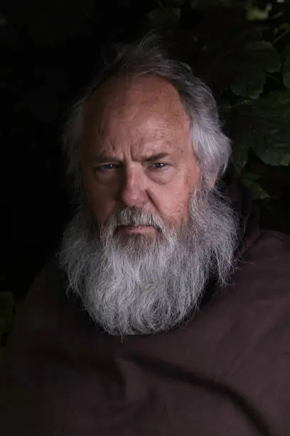 Elderly monk wearing a brown habit.