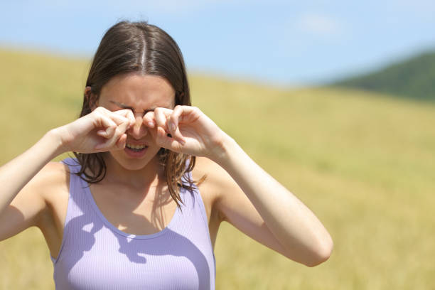 Allergic woman scratching eyes in a wheat field