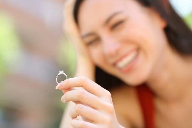 Happy asian woman looking at engagement ring