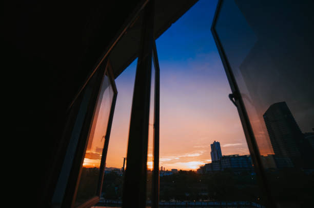 istock Sunset looking through window at city with reflection on window with sunset sun 1325896044