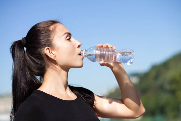istock Attractive sporty model drinking water during running at the park in sunny morning. Empty space 1325896363