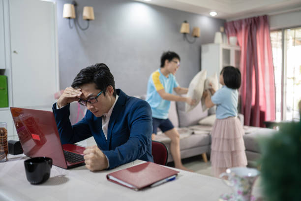 asian chinese man work at home. children were having playing in pillow fights. father loss concentration and frustrated. - inconvenience meeting business distracted imagens e fotografias de stock