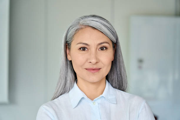Happy confident middle aged Asian older senior female lawyer businesswoman corporation ceo in modern office looking at camera. Business woman executive concept. Closeup portrait headshot. Happy confident middle aged Asian older senior female lawyer businesswoman corporation ceo in modern office looking at camera. Business woman executive concept. Closeup portrait headshot. 40 49 years stock pictures, royalty-free photos & images
