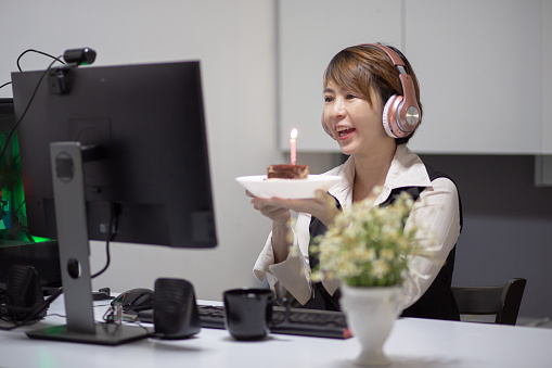 Asian Chinese woman work in home office celebrating her birthday video conference with her colleague at other branch