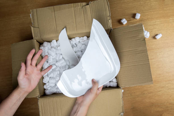 Broken plate in damaged cardboard box top view, damaged home delivery unpacking box stock photo