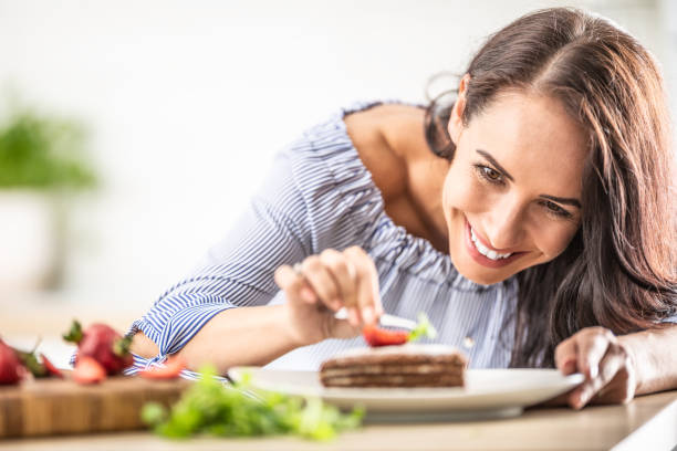 istock Smiling woman decorates finished cake with tweezers. 1325901971