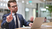 Young Businessman with Laptop showing No Gesture, Disapprove