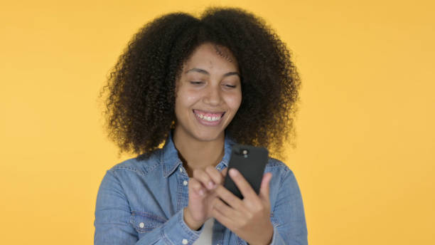 istock Young African Woman using Smartphone, Yellow Background 1325907178