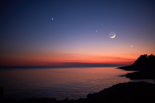 Silueta de un hombre mirando a la Luna y estrellas sobre el horizonte del océano marino. photo