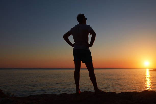 istock Silhouette of a man watching sunset over distant horizon. 1325908277