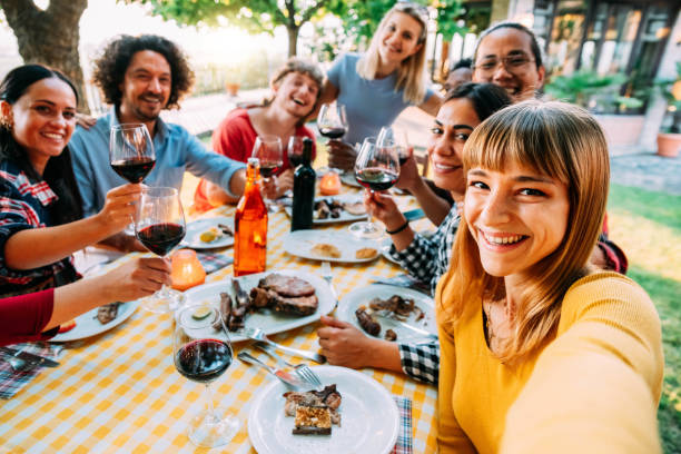 grupa szczęśliwych przyjaciół robiących selfie na grillu na kolacji na świeżym powietrzu w restauracji w ogrodzie - wielorasowe młode osoby jedzące jedzenie i bawiące się na grillu na podwórku - koncepcja młodzieży i przyjaźni - stół piknikowy zdjęcia i obrazy z banku zdjęć