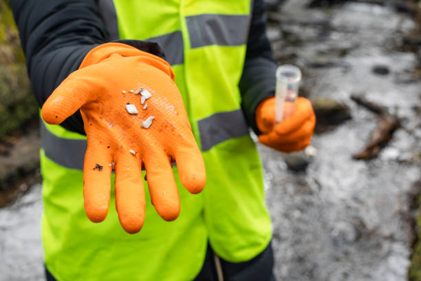 Water Contaminated By Plastic A close-up of a female scientist holding up a collection of small plastics she has found whilst collecting samples of water in Hexham in the North East of England. microplastic photos stock pictures, royalty-free photos & images