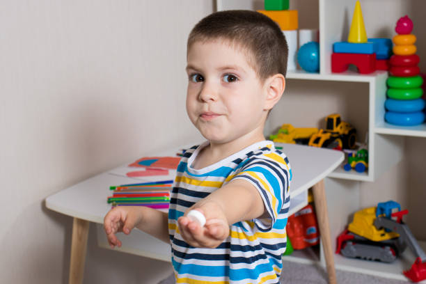 istock A small child and a white vitamin pill. 1325911427