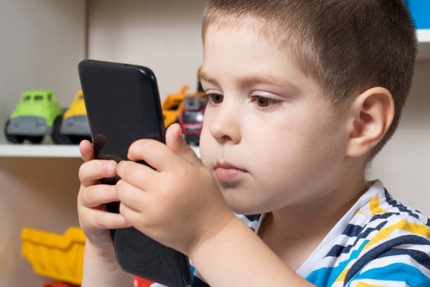 istock A little boy 3-4 years old looks into the phone screen. 1325911440