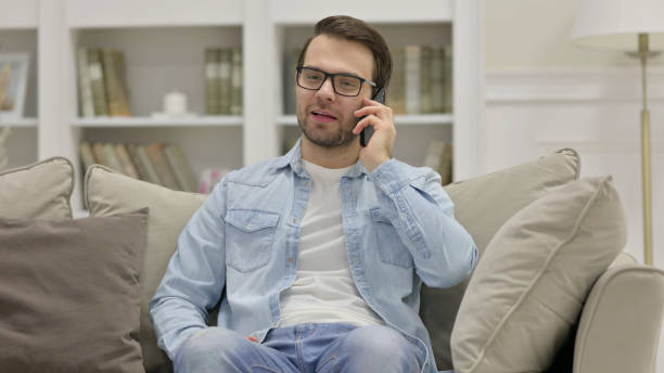 istock Young Man Talking on Smartphone at Home 1325912981