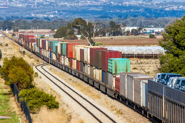 vista de alto ángulo de contenedores de carga y vehículos de motor en un tren de carga largo en la zona rural - shunting yard freight train cargo container railroad track fotografías e imágenes de stock