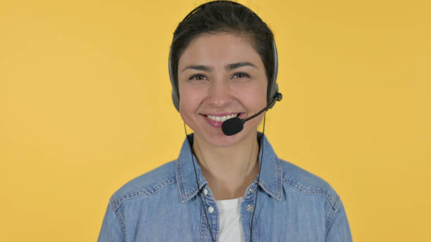 istock Indian Woman with Headset Smiling at Camera, Yellow Background 1325913214