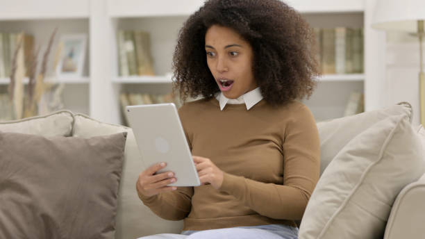 istock Success, Young African Woman Celebrating On Tablet on Sofa 1325915800