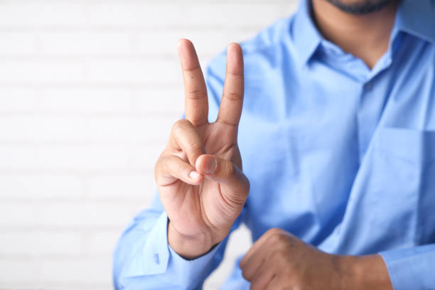 istock man hand showing victory gesture on white background 1325915827