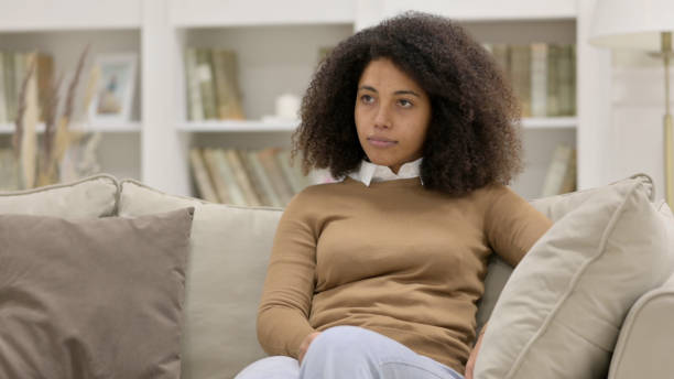 istock Young African Woman Coming and Sitting on Sofa 1325915864