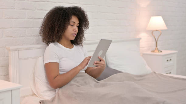 istock Relaxing Young African Woman Using Tablet in Bed 1325915879