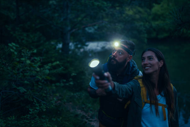 istock Young couple holding flashlights in the woods 1325915909