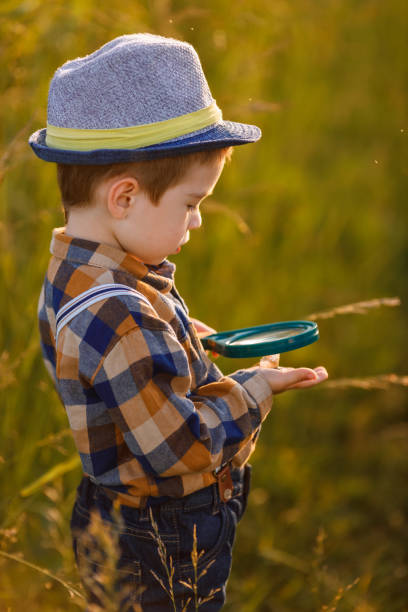 istock little boy exploring nature in the meadow with a magnifying glass 1325917587