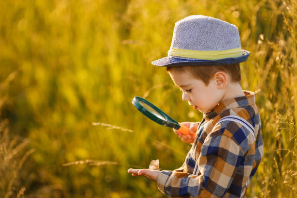 istock little boy exploring nature in the meadow with a magnifying glass 1325917598