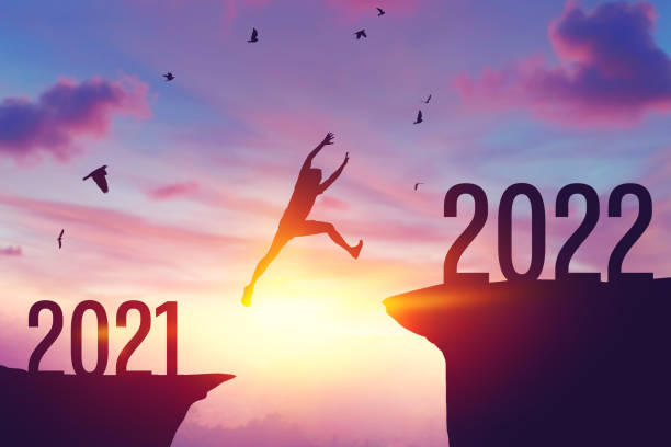 Silhouette man jumping between cliff with number 2021 to 2022 and birds flying at top of mountain. Freedom challenge and travel adventure holiday concept. Silhouette man jumping between cliff with number 2021 to 2022 and birds flying at top of mountain. Freedom challenge and travel adventure holiday concept. Vintage tone filter effect color style. 2021 stock pictures, royalty-free photos & images