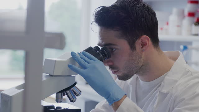 Male scientist using microscope for cultured meat examination