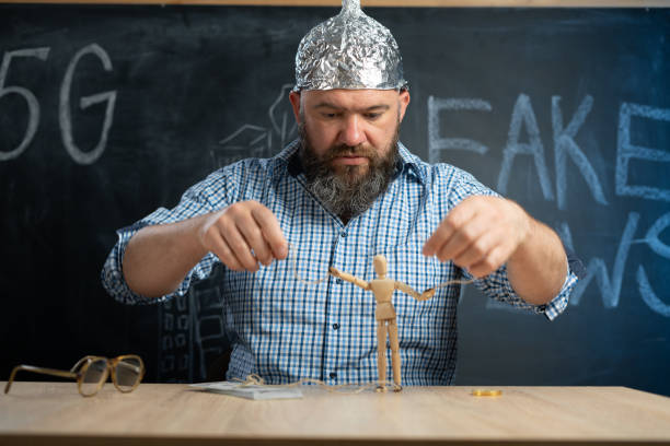 a distraught schizophrenic conspiracy theorist in a protective foil cap controls a man - a toy. Consciousness manipulation. Conspiracy theory. Mind control. Copy space