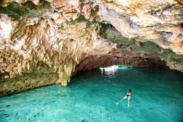 Woman swimming in freshwater Cenote in Cancun Mexico.