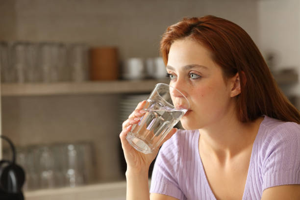 istock Woman drinking water from glass in the kitchen 1325920125