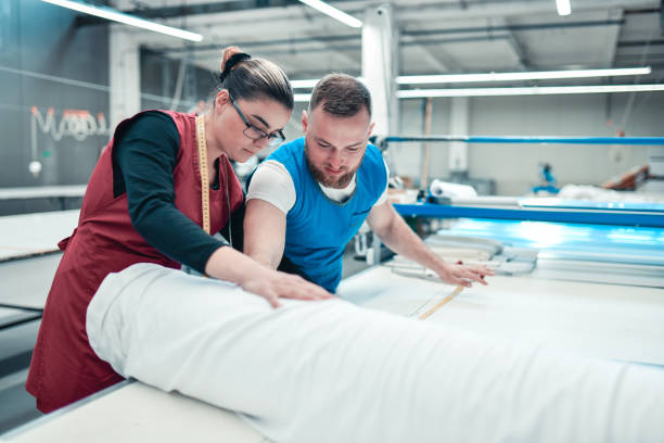 istock Male And Female Textile Workers Setting Up Print Roller Material In Textile Factory 1325920136