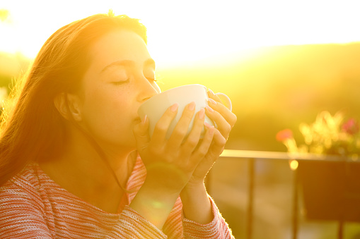Woman relaxing drinking coffee at sunset
